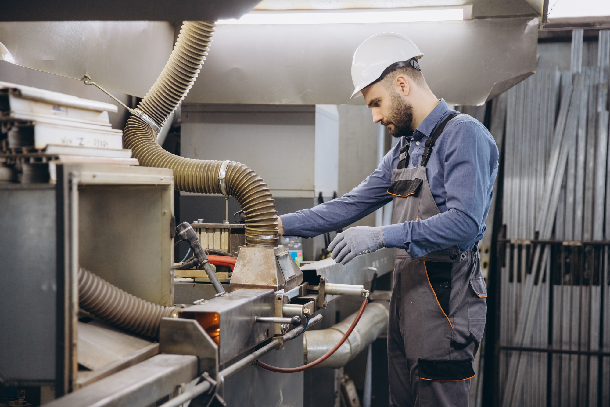 Factory worker operating machinery for aluminum and PVC windows and doors production