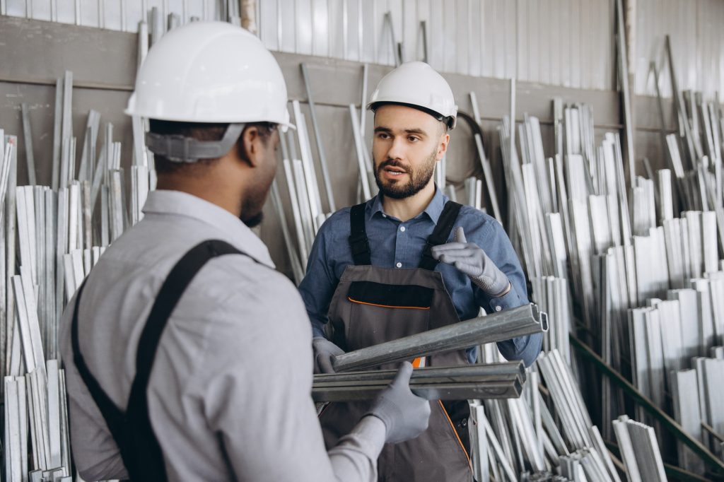 Two factory workers discussing aluminum profiles for windows and doors production